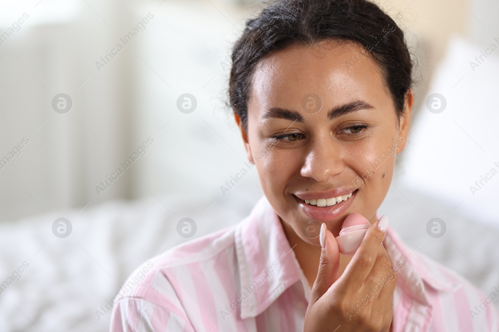 Photo of Smiling woman with lip balm on blurred background. Space for text