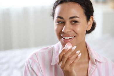 Photo of Smiling woman with lip balm on blurred background. Space for text