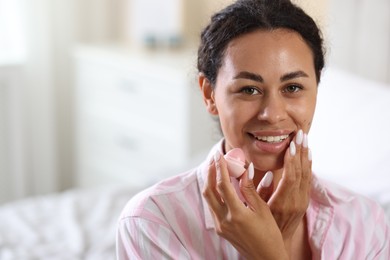 Photo of Smiling woman with lip balm on blurred background. Space for text