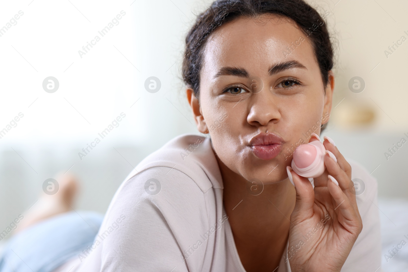 Beautiful woman with lip balm on blurred background, closeup Photo of Beautiful woman with lip balm on blurred background, closeup