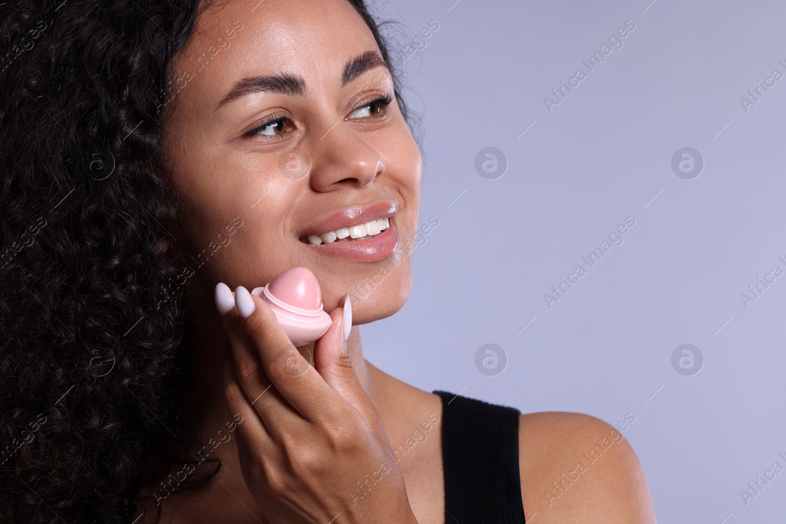 Smiling woman with lip balm on grey background, closeup Photo of Smiling woman with lip balm on grey background, closeup