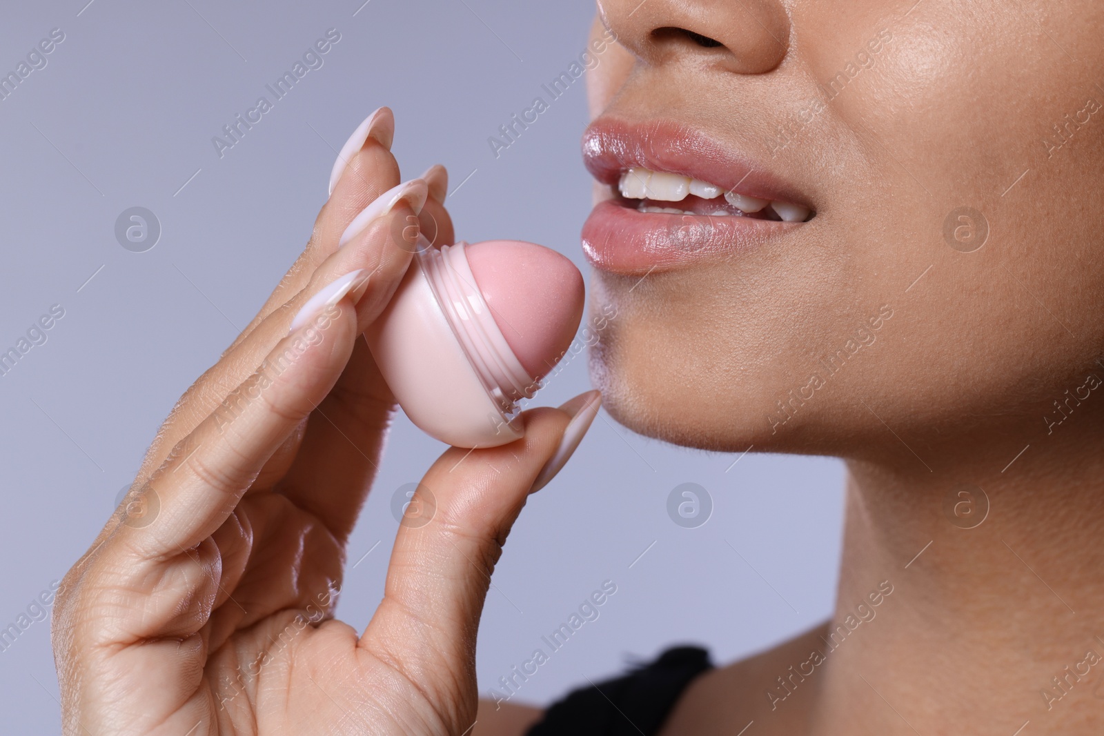 Smiling woman with lip balm on grey background, closeup Photo of Smiling woman with lip balm on grey background, closeup