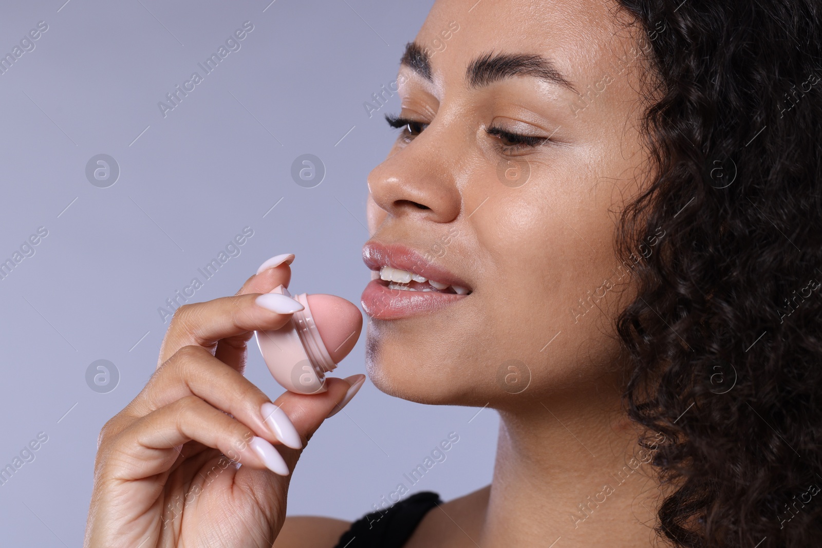 Smiling woman with lip balm on grey background, closeup Photo of Smiling woman with lip balm on grey background, closeup