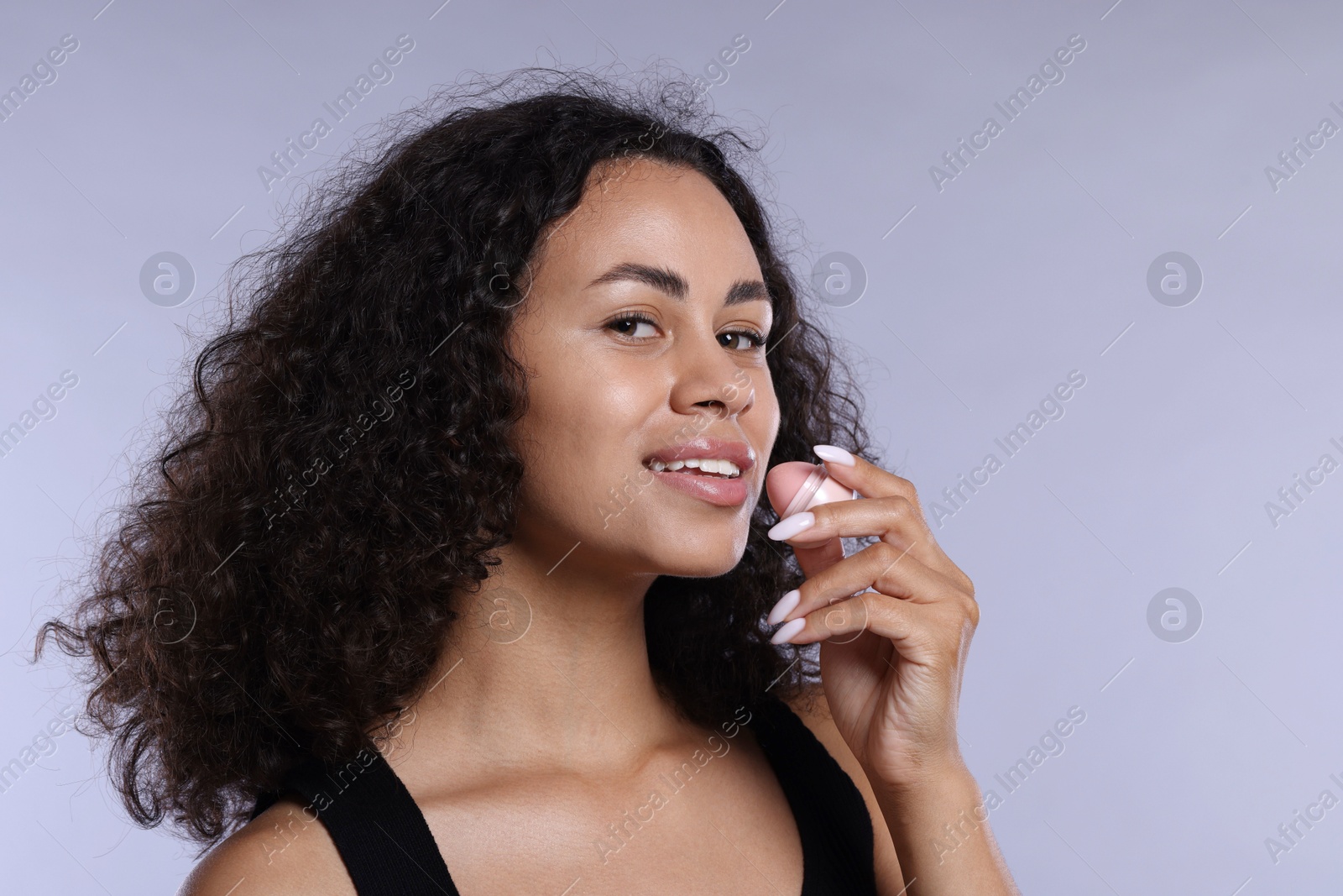 Smiling woman with lip balm on grey background, closeup Photo of Smiling woman with lip balm on grey background, closeup