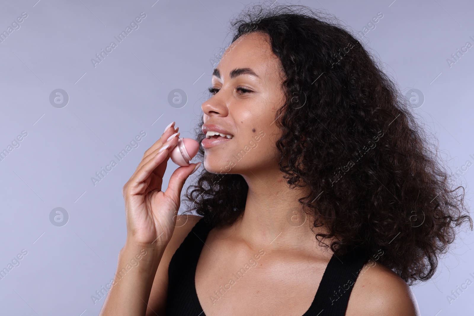 Photo of Smiling woman with lip balm on grey background
