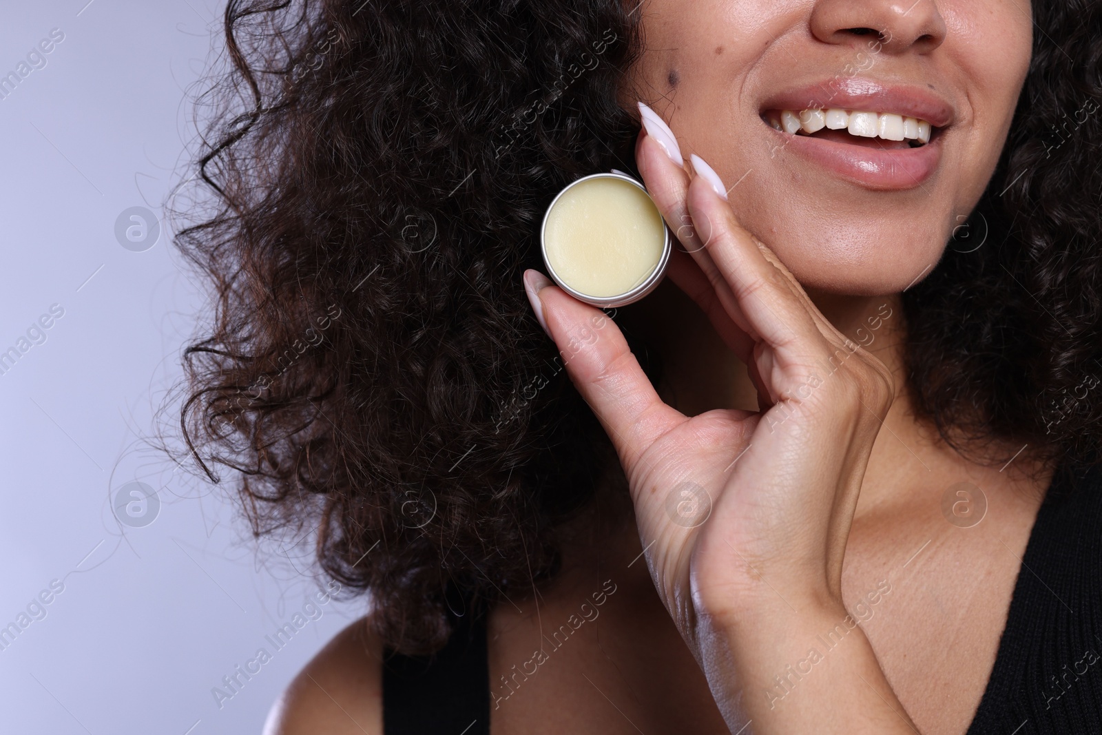 Photo of Smiling woman with lip balm on grey background, closeup