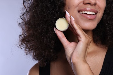 Photo of Smiling woman with lip balm on grey background, closeup