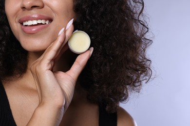 Photo of Smiling woman with lip balm on grey background, closeup