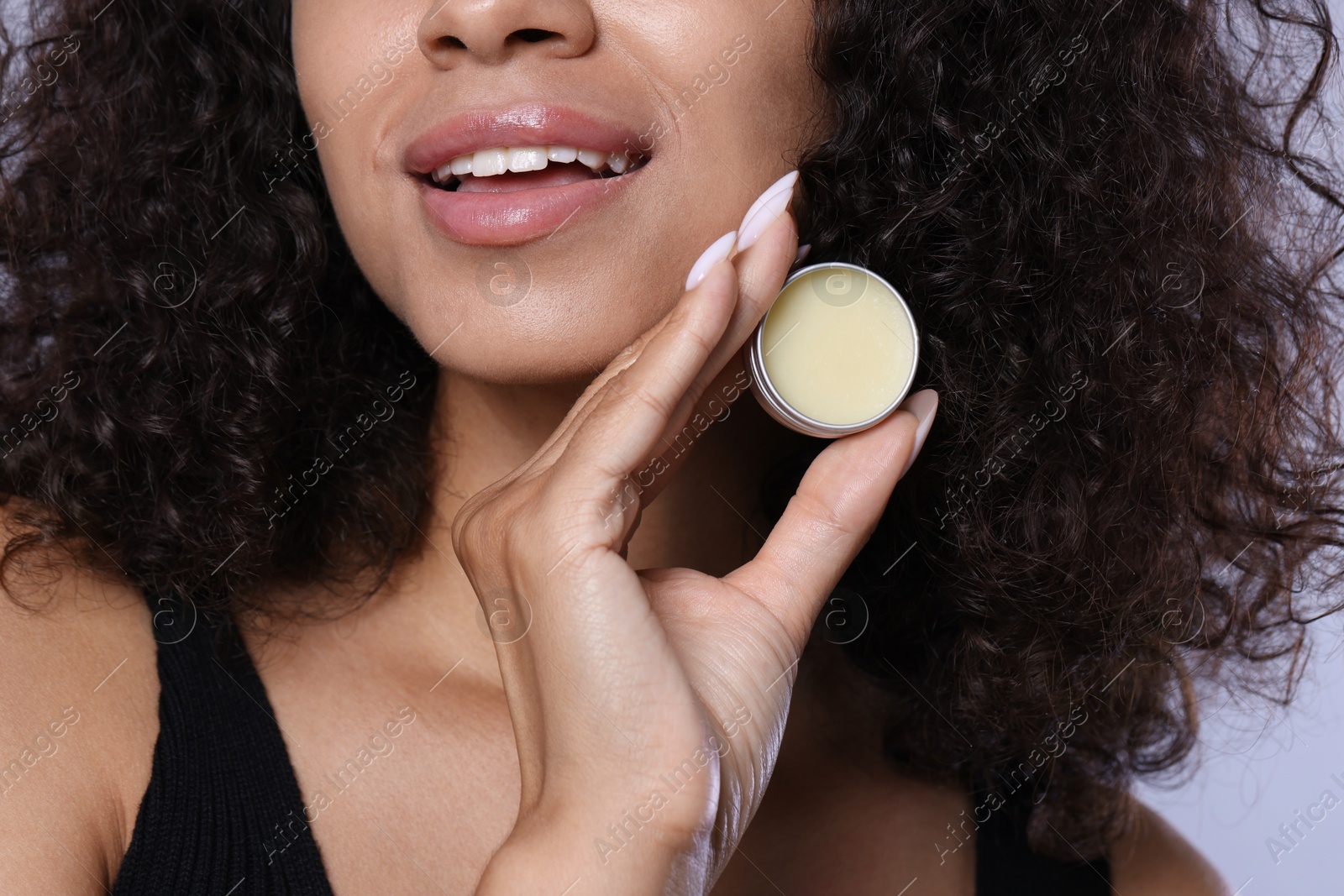 Photo of Smiling woman with lip balm on grey background, closeup