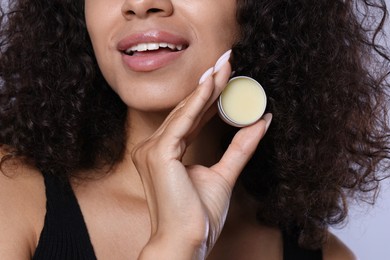 Photo of Smiling woman with lip balm on grey background, closeup