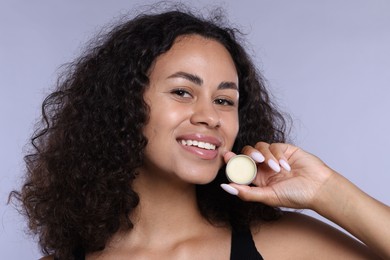 Photo of Smiling woman with lip balm on grey background, closeup