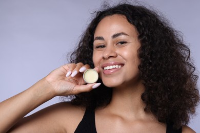 Photo of Smiling woman with lip balm on grey background, closeup