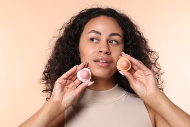 Photo of Smiling woman with containers of lip balm on beige background