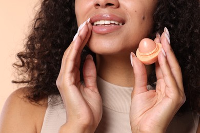 Photo of Smiling woman with lip balm on beige background, closeup