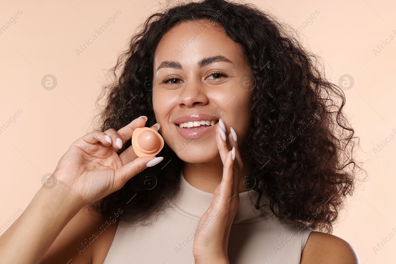 Smiling woman with lip balm on beige background, closeup Photo of Smiling woman with lip balm on beige background, closeup