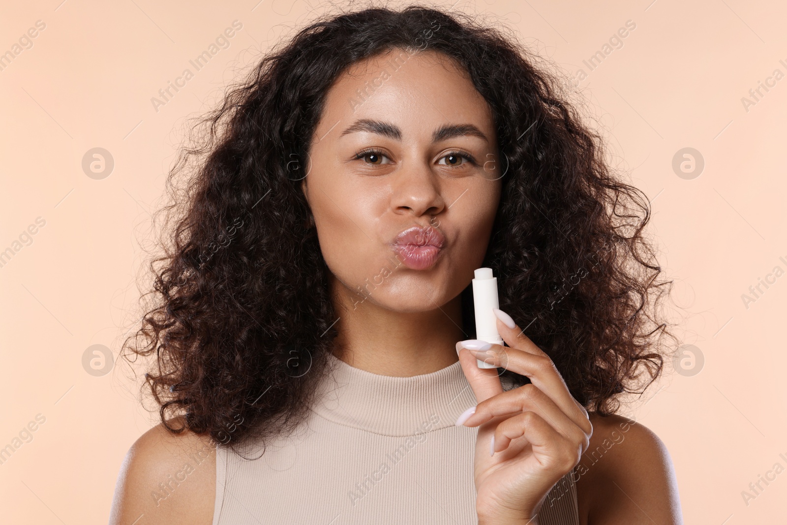 Beautiful woman with lip balm on beige background Photo of Beautiful woman with lip balm on beige background
