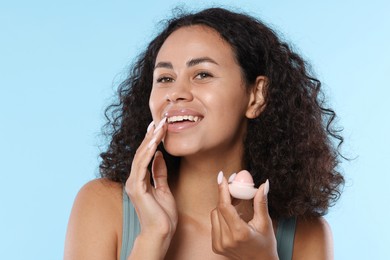 Photo of Smiling woman with lip balm on light blue background