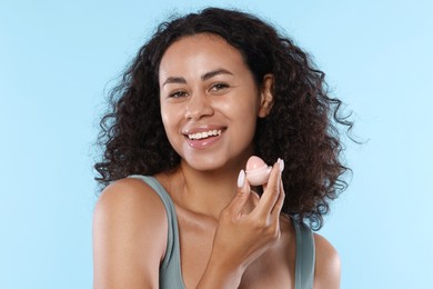Photo of Smiling woman with lip balm on light blue background