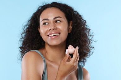 Photo of Smiling woman with lip balm on light blue background