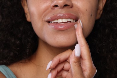Photo of Smiling woman applying lip balm onto her lips, closeup