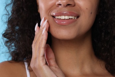 Photo of Smiling woman with glossy lip balm on her lips, closeup