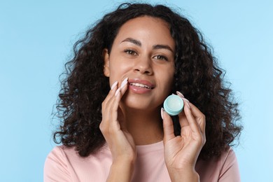 Photo of Smiling woman with lip balm on light blue background