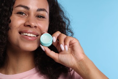 Photo of Smiling woman with lip balm on light blue background