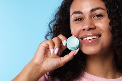 Photo of Smiling woman with lip balm on light blue background