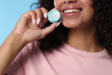 Photo of Smiling woman with lip balm on light blue background