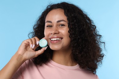 Photo of Smiling woman with lip balm on light blue background