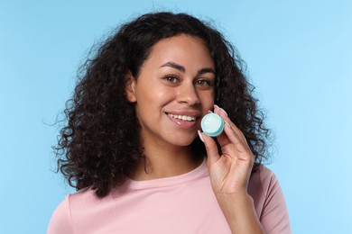 Photo of Smiling woman with lip balm on light blue background