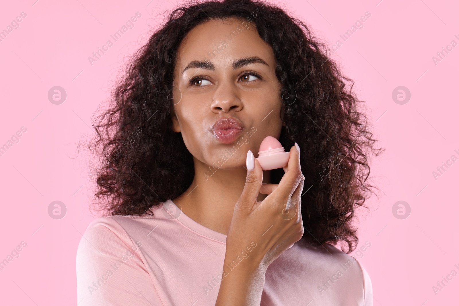 Beautiful woman with lip balm on pink background Photo of Beautiful woman with lip balm on pink background