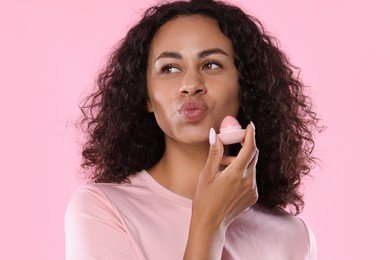 Photo of Beautiful woman with lip balm on pink background