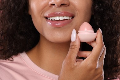 Photo of Smiling woman with container of lip balm, closeup