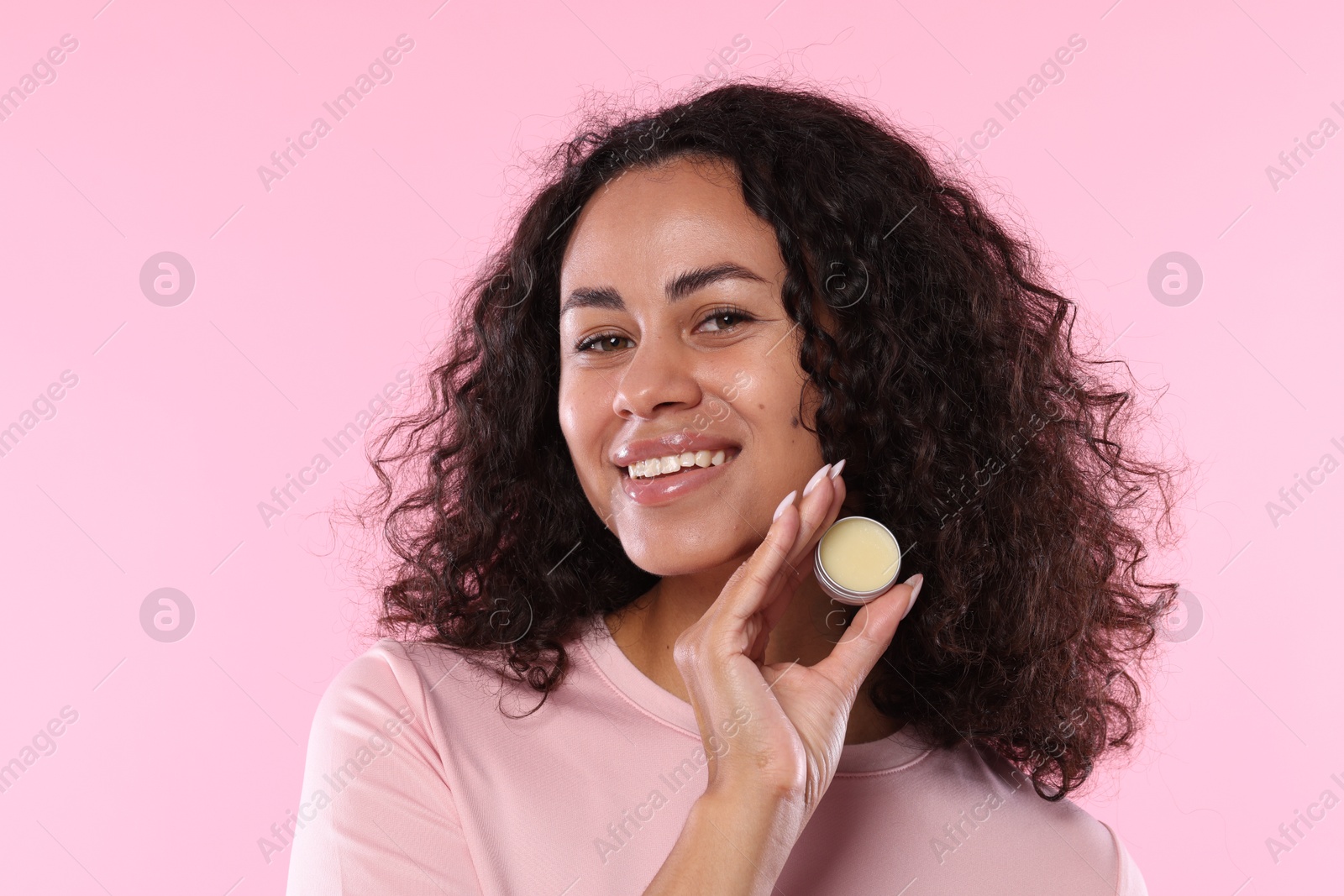 Smiling woman with lip balm on pink background Photo of Smiling woman with lip balm on pink background
