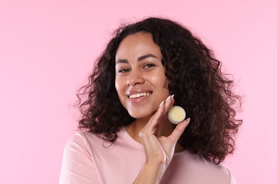 Photo of Smiling woman with lip balm on pink background