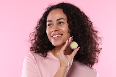 Photo of Smiling woman with lip balm on pink background