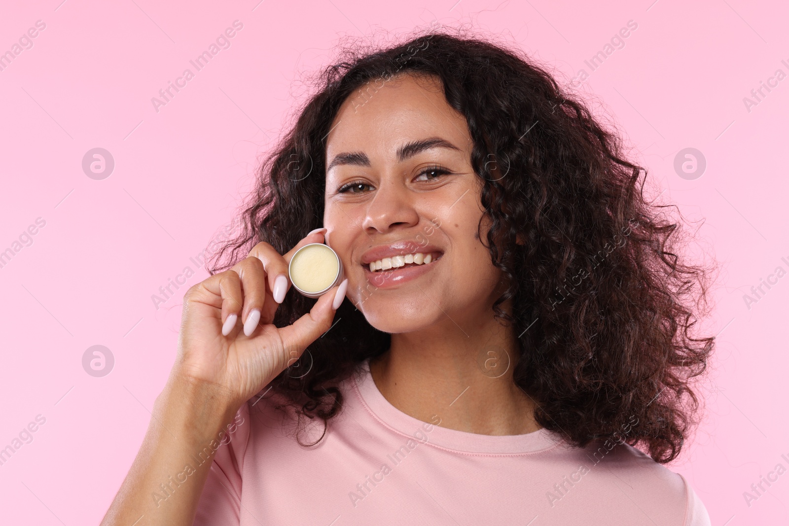 Smiling woman with lip balm on pink background Photo of Smiling woman with lip balm on pink background