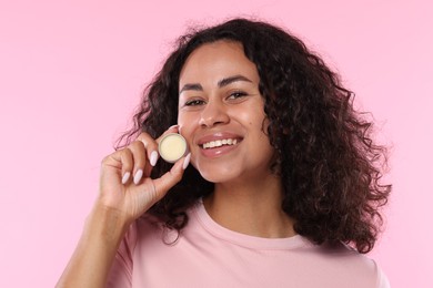 Photo of Smiling woman with lip balm on pink background