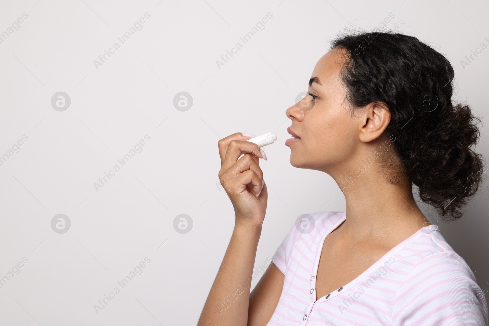Beautiful woman applying lip balm onto her lips on grey background. Space for text Photo of Beautiful woman applying lip balm onto her lips on grey background. Space for text