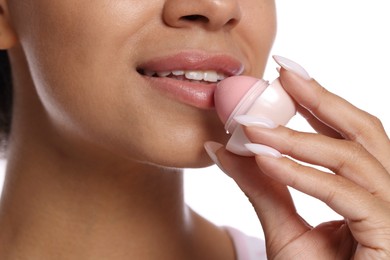 Photo of Smiling woman applying lip balm onto her lips on white background, closeup