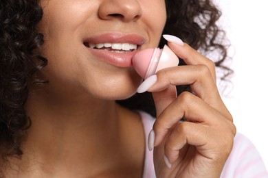 Photo of Smiling woman applying lip balm onto her lips on white background, closeup