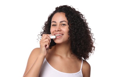 Photo of Smiling woman applying lip balm onto her lips on white background