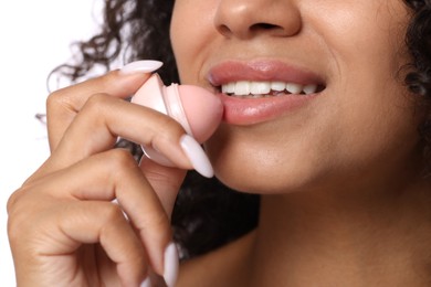 Photo of Smiling woman applying lip balm onto her lips on white background, closeup