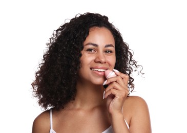 Photo of Smiling woman applying lip balm onto her lips on white background