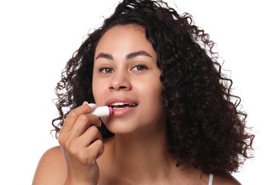 Photo of Beautiful woman applying lip balm onto her lips on white background, closeup