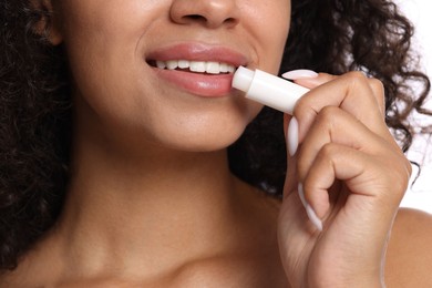 Photo of Smiling woman applying lip balm onto her lips, closeup