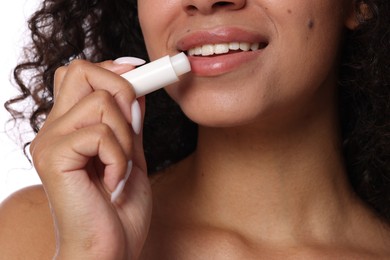 Photo of Smiling woman applying lip balm onto her lips, closeup