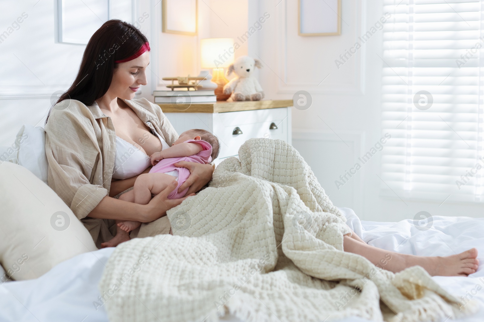 Mother with her newborn baby on bed indoors Photo of Mother with her newborn baby on bed indoors