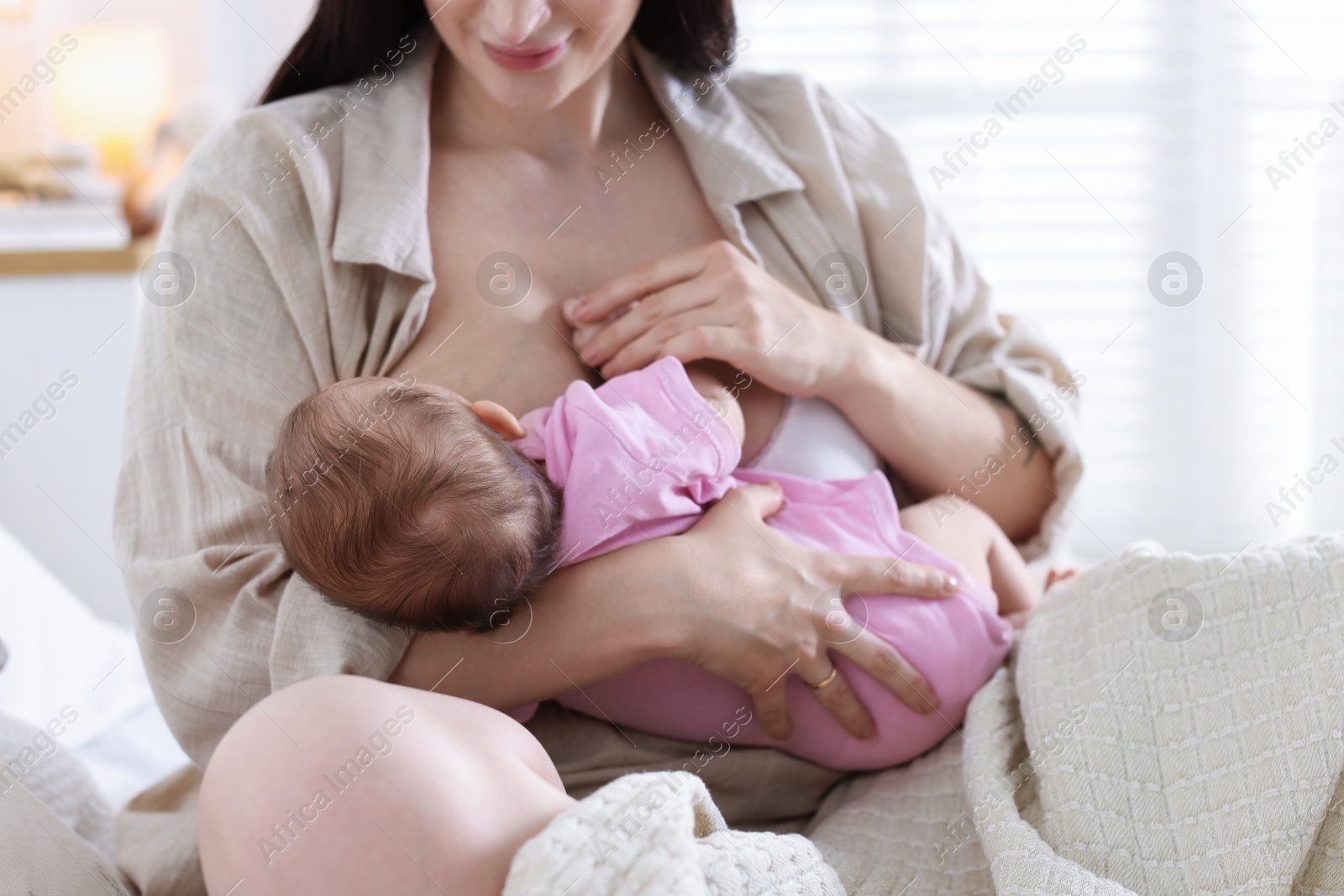 Mother breastfeeding her newborn baby on bed indoors, closeup Photo of Mother breastfeeding her newborn baby on bed indoors, closeup
